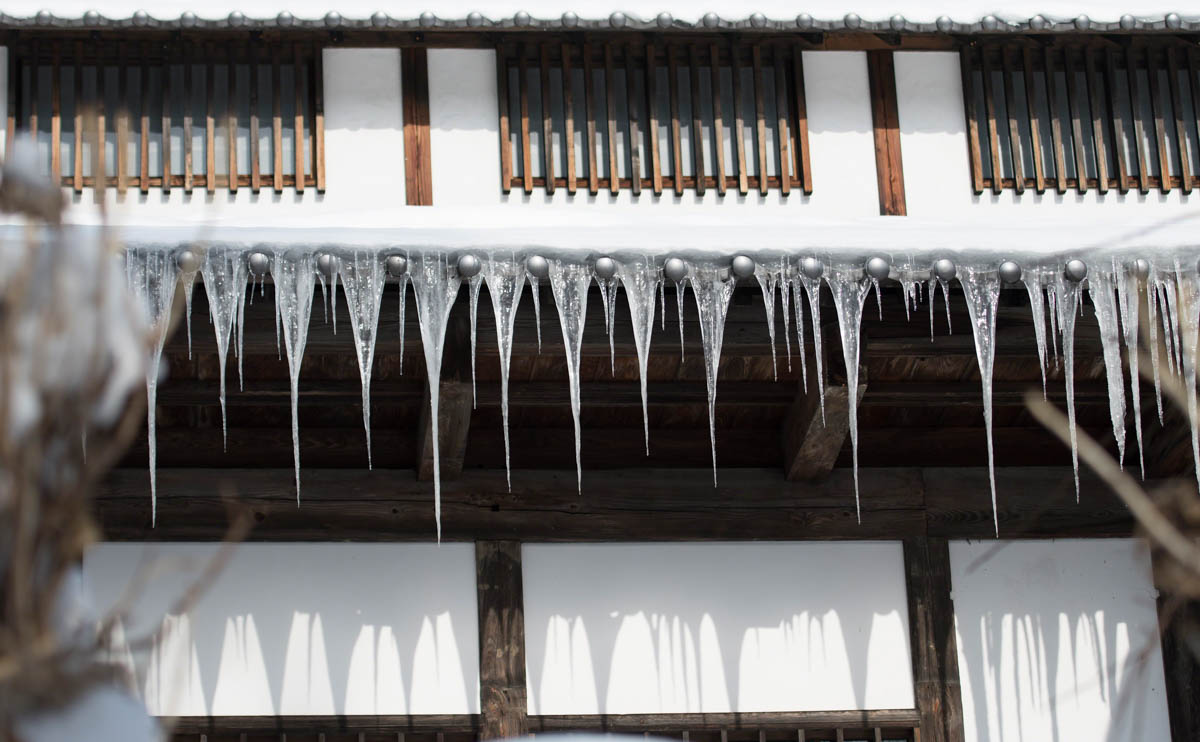 Alpine house with long icicles hanging from roof. Nagano, Japan
