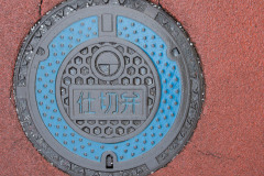 Decorative manhole cover with blue circle and pick background, Tokyo, Japan