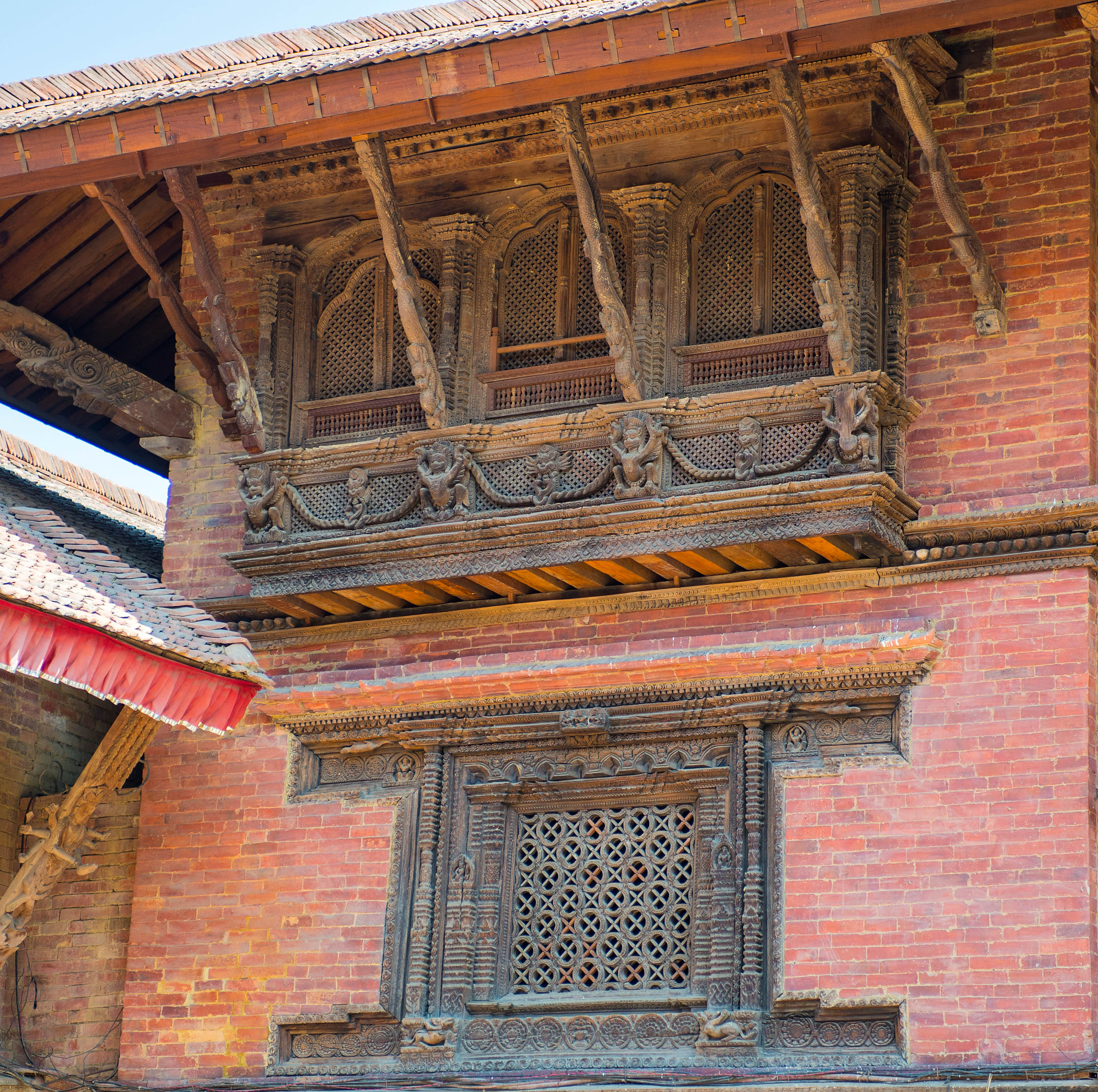 Beautiful carved wooden windows on building, with pink brickwork