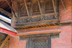 Beautiful carved wooden windows on building, with pink brickwork
