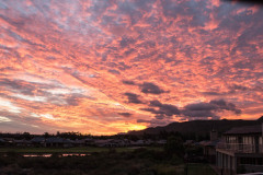 Stunning sunset behind cloudy sky with sunset reflecting on water inforefront